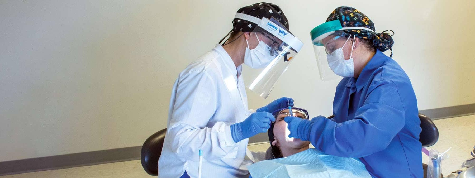 2 dental students working on a patient